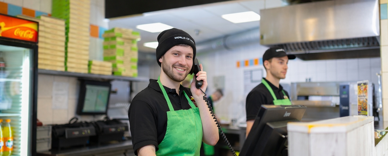 Eine Frau in grüner Schürze telefoniert.