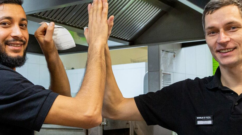 Zwei Männer geben sich in einer Küche gegenseitig High Fives.
